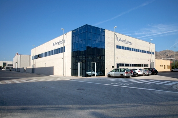 Edificio de las instalaciones de Derbós con fachada de vidrio y coches aparcados