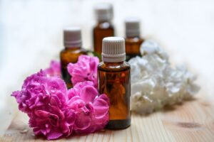 Frascos de aceite esencial de vidrio ámbar junto a flores rosas y blancas sobre madera