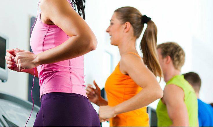 Personas con ropa deportiva corriendo en cintas de gimnasio durante una sesión de ejercicio