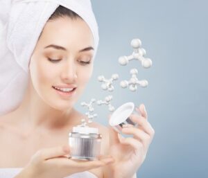 Mujer con toalla en la cabeza sostiene un tarro de crema hidratante con moléculas activas flotando