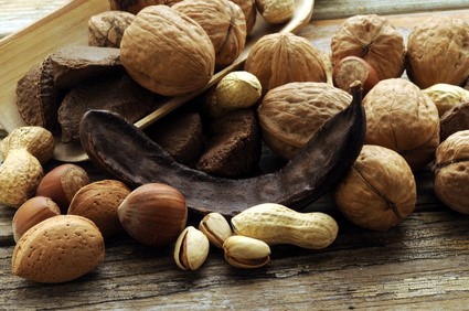 Frutos secos variados con nueces, almendras, avellanas, cacahuetes, pistachos y algarroba sobre madera