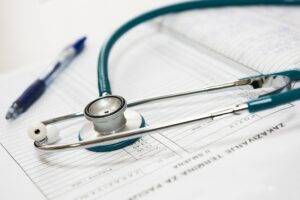 Estetoscopio verde y bolígrafo azul sobre un formulario médico impreso