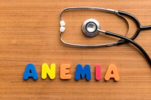 Palabra Anemia formada con letras de colores junto a un estetoscopio sobre mesa de madera