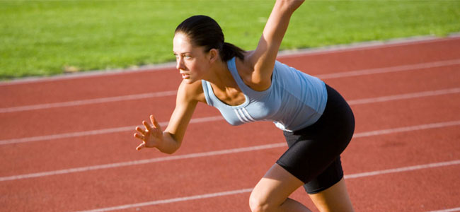 Mujer deportista corriendo en pista de atletismo al aire libre