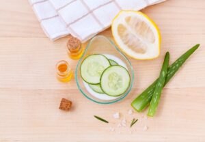 Ingredientes de cosmética natural con pepino, aloe vera, limón, aceites y sal marina sobre madera