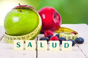 Manzana verde y roja con cinta métrica, frutos rojos y cubos que forman la palabra SALUD