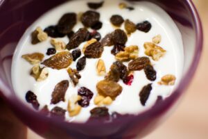 Yogur natural con pasas y nueces en un cuenco morado