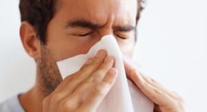 Hombre con barba sonándose la nariz con un pañuelo por síntomas de resfriado