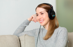 Mujer sonriente con auriculares realizando una prueba de audición sentada en un sofá