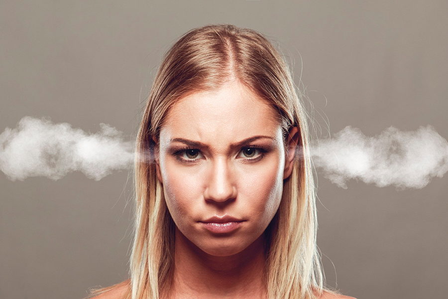 Mujer rubia enfadada con vapor saliendo de sus oídos sobre fondo gris