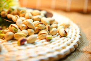Pistachos tostados con cáscara abierta sobre un mantel de fibra natural trenzada
