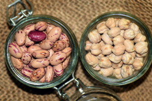 Tarros de vidrio con alubias pintas y garbanzos secos sobre tela de yute
