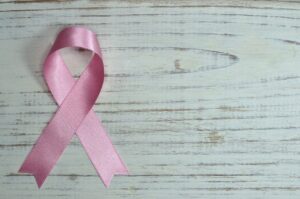 Lazo rosa de raso símbolo de la lucha contra el cáncer de mama sobre madera clara