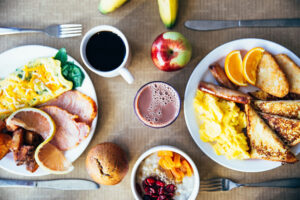 Desayuno completo con huevos, tostadas, salchichas, café, fruta y avena visto desde arriba