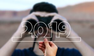 Persona mirando con prismáticos hacia el horizonte con el número 2019 dibujado en primer plano