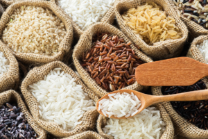 Variedades de arroz blanco, integral, rojo y negro en sacos de yute con cucharas de madera