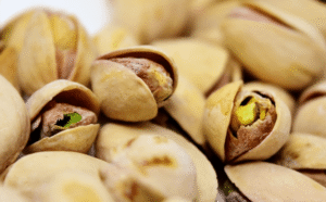 Pistachos tostados con cáscara abierta mostrando el fruto verde en primer plano