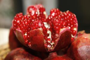Granada abierta con granos rojos brillantes sobre otras granadas maduras