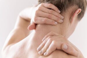 Mujer con las manos sujetándose el cuello y el hombro por dolor muscular y tensión cervical