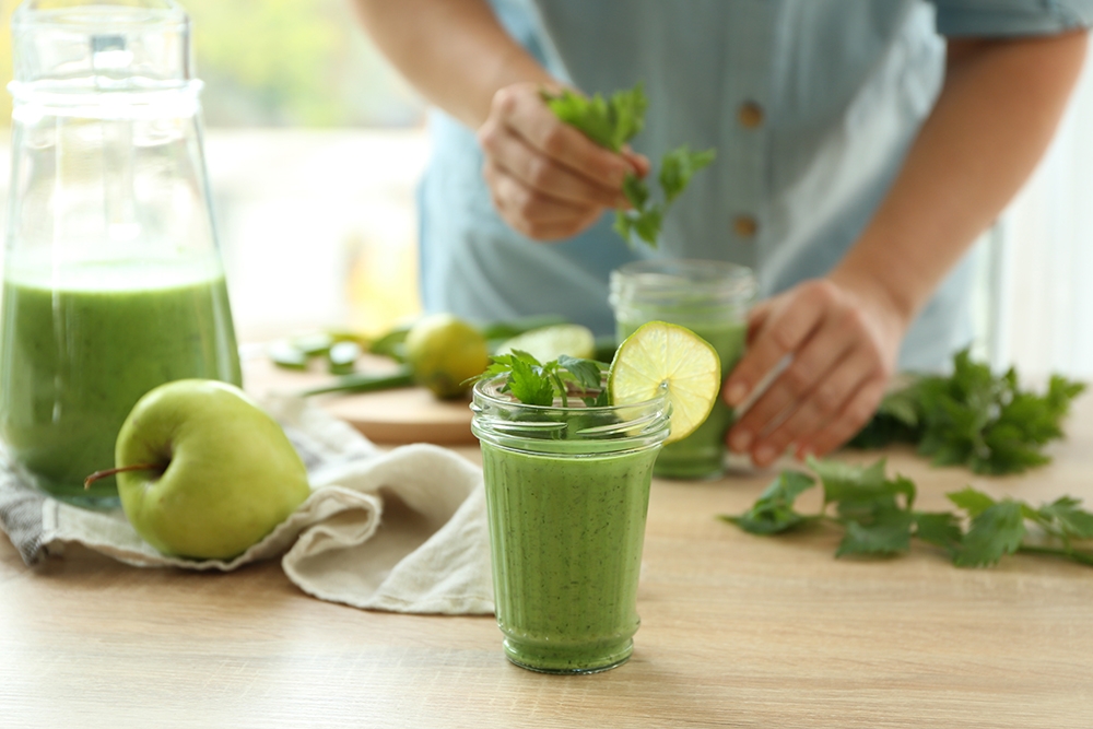 Batido verde depurativo de manzana y perejil con rodaja de lima en vaso sobre mesa de madera