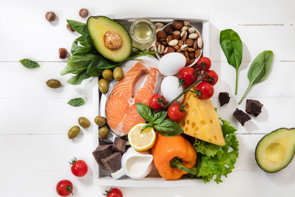Bandeja con salmón, aguacate, huevos, frutos secos, aceite y verduras ricos en omegas