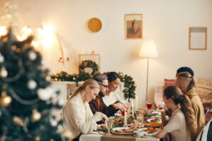 Familia y amigos reunidos alrededor de una mesa navideña con velas y árbol de Navidad