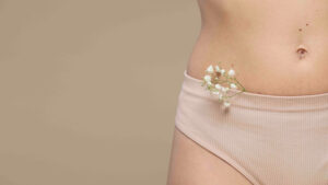 Vientre de mujer en ropa interior beige con flores blancas de gypsophila sobre la cadera