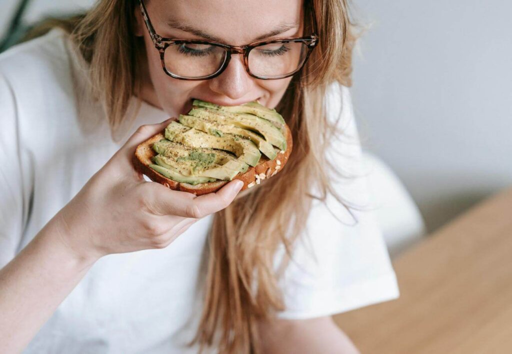 Mujer comiendo una tostada con aguacate