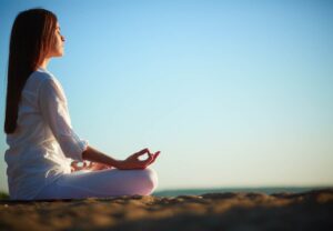 Mujer relajada meditando al borde del mar