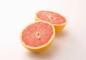 Pomelo rosado cortado por la mitad mostrando su pulpa jugosa sobre fondo blanco