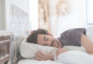 Hombre durmiendo plácidamente en una cama con sábanas blancas
