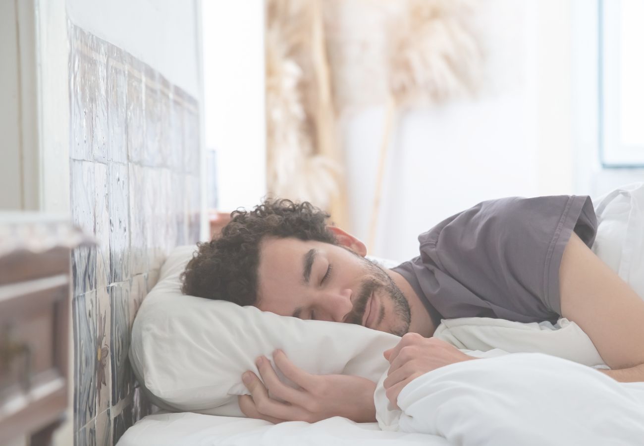 Hombre durmiendo plácidamente en una cama con sábanas blancas