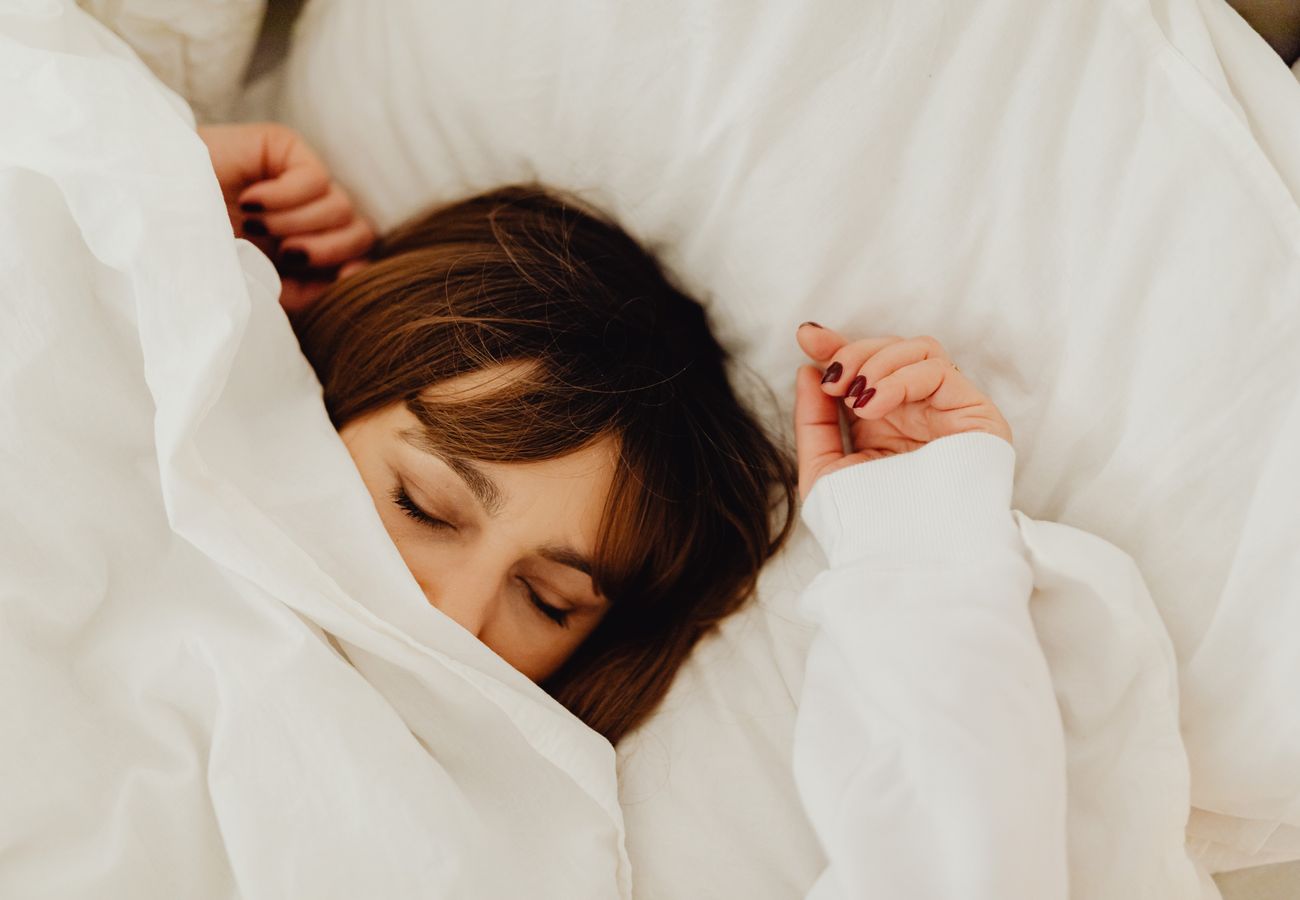Mujer descansando en la cama representando el equilibrio emocional y el bienestar mental