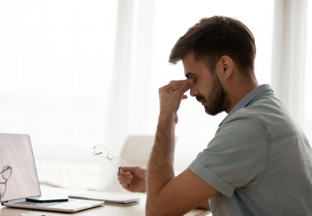 Hombre cansado frente al ordenador, señal de posible déficit de vitamina B12