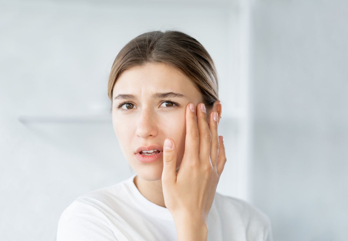 Mujer joven observando signos de cansancio y envejecimiento en su piel